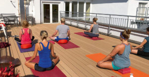 Menschen beim Yoga auf Dachterasse